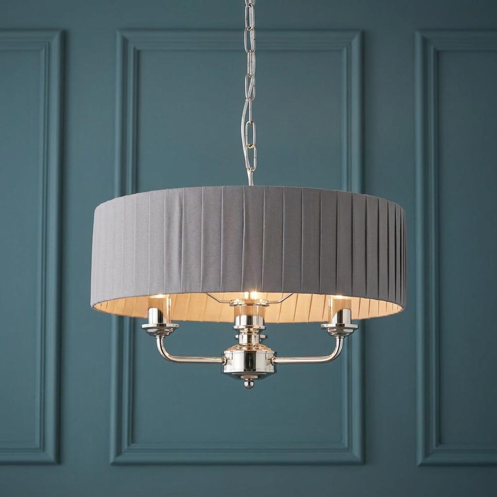 3-light pendant featuring a charcoal pleated shade and bright nickel finish set against a teal paneled wall.