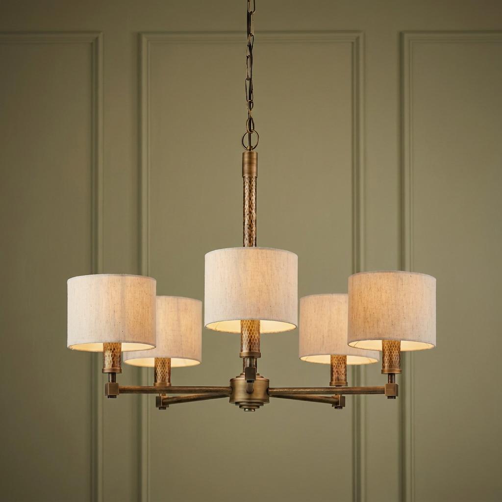 Aged bronze five-light ceiling pendant with cream drum shades against a paneled green wall.