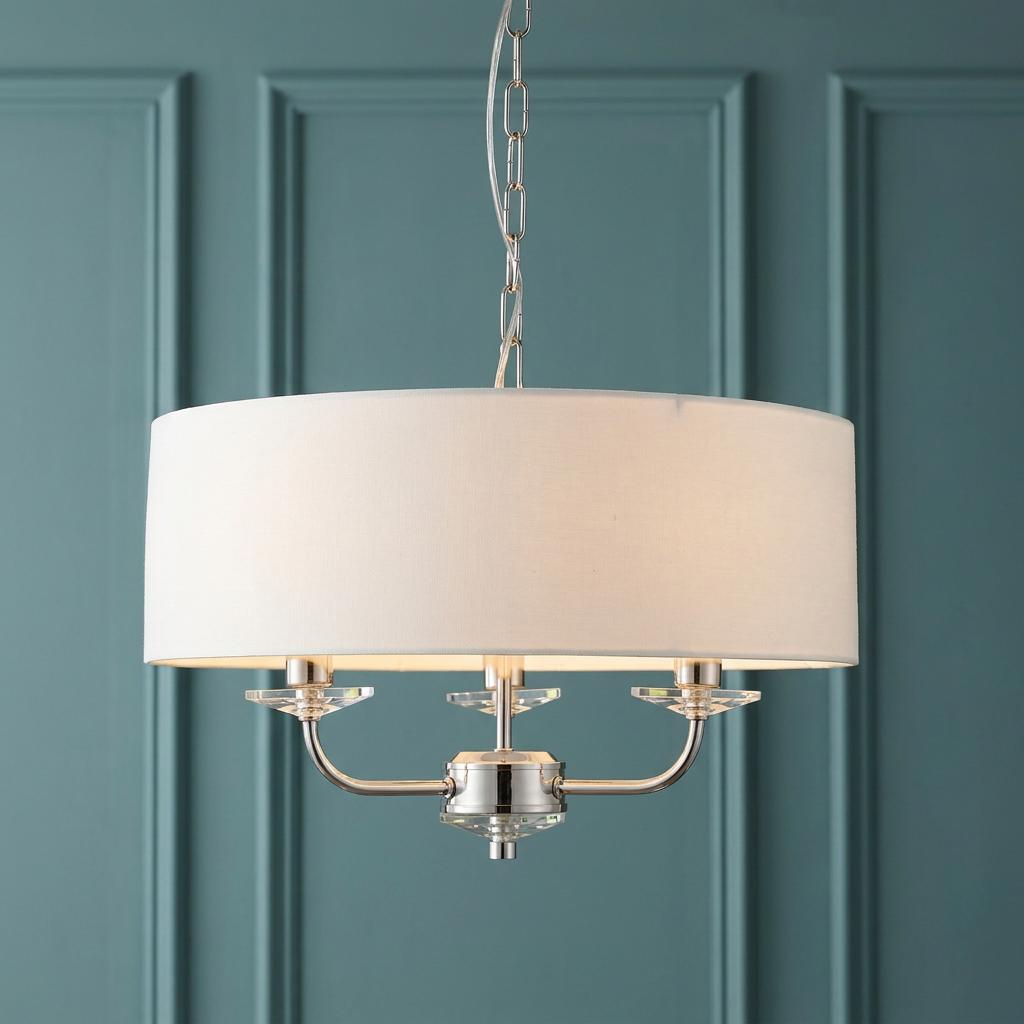 Endon Nixon 3-light pendant with a white drum shade and nickel finish against a teal paneled wall.