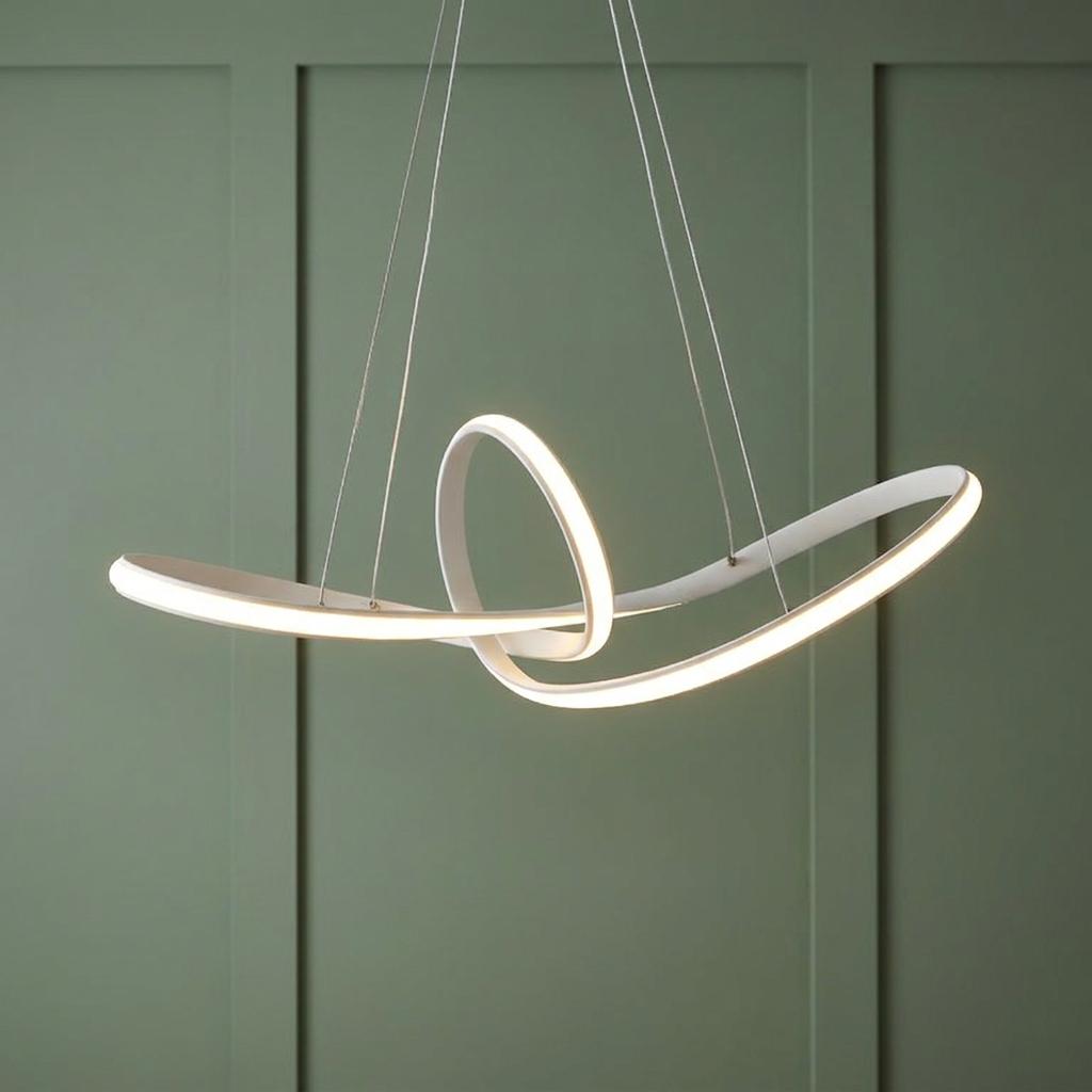 A modern white LED pendant light in a sculptural loop design suspended against a green panelled wall.