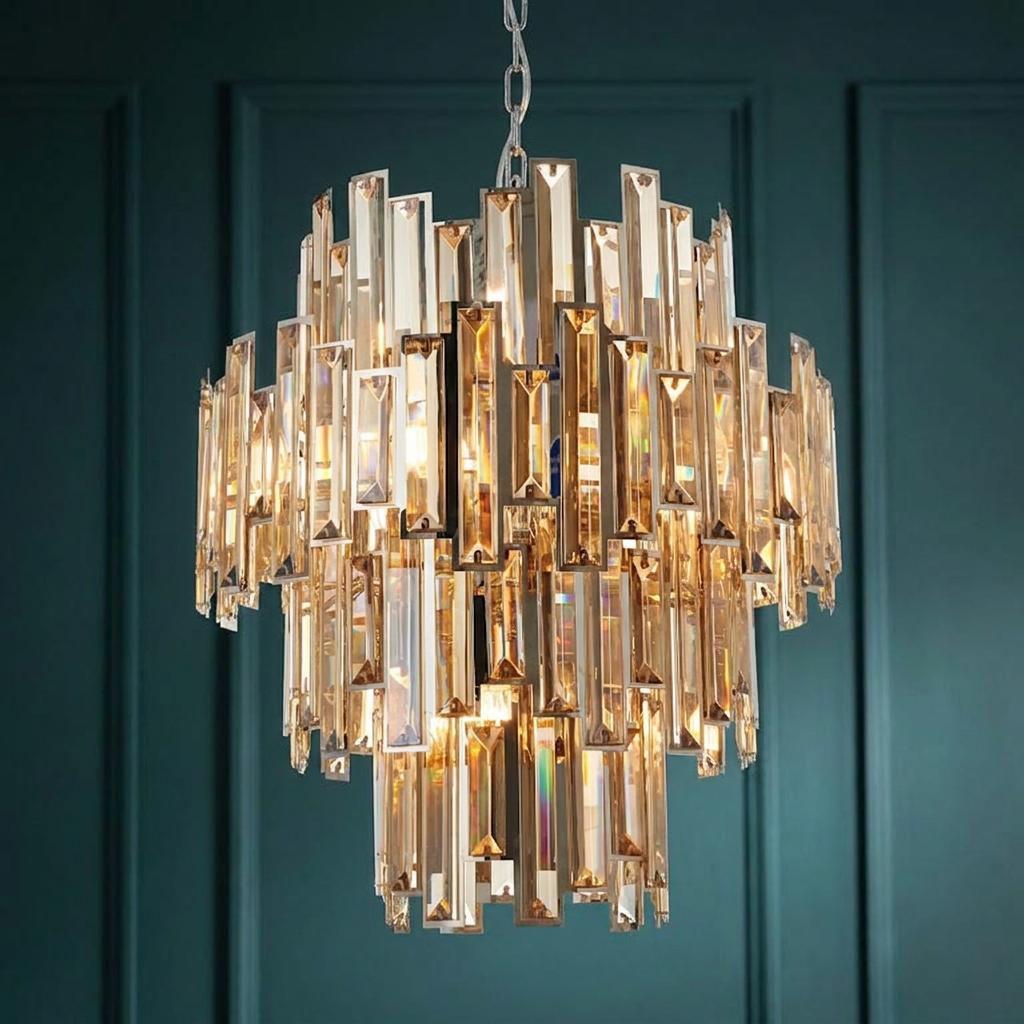 Tiered chandelier with rectangular tinted champagne crystals against a teal paneled wall.