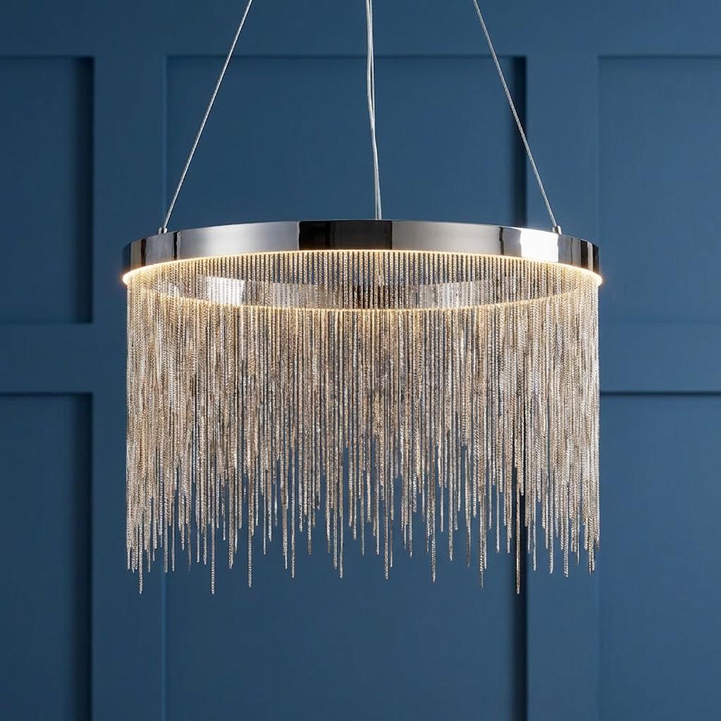 Chrome circular pendant light featuring cascading silver chains against a navy blue paneled wall background.