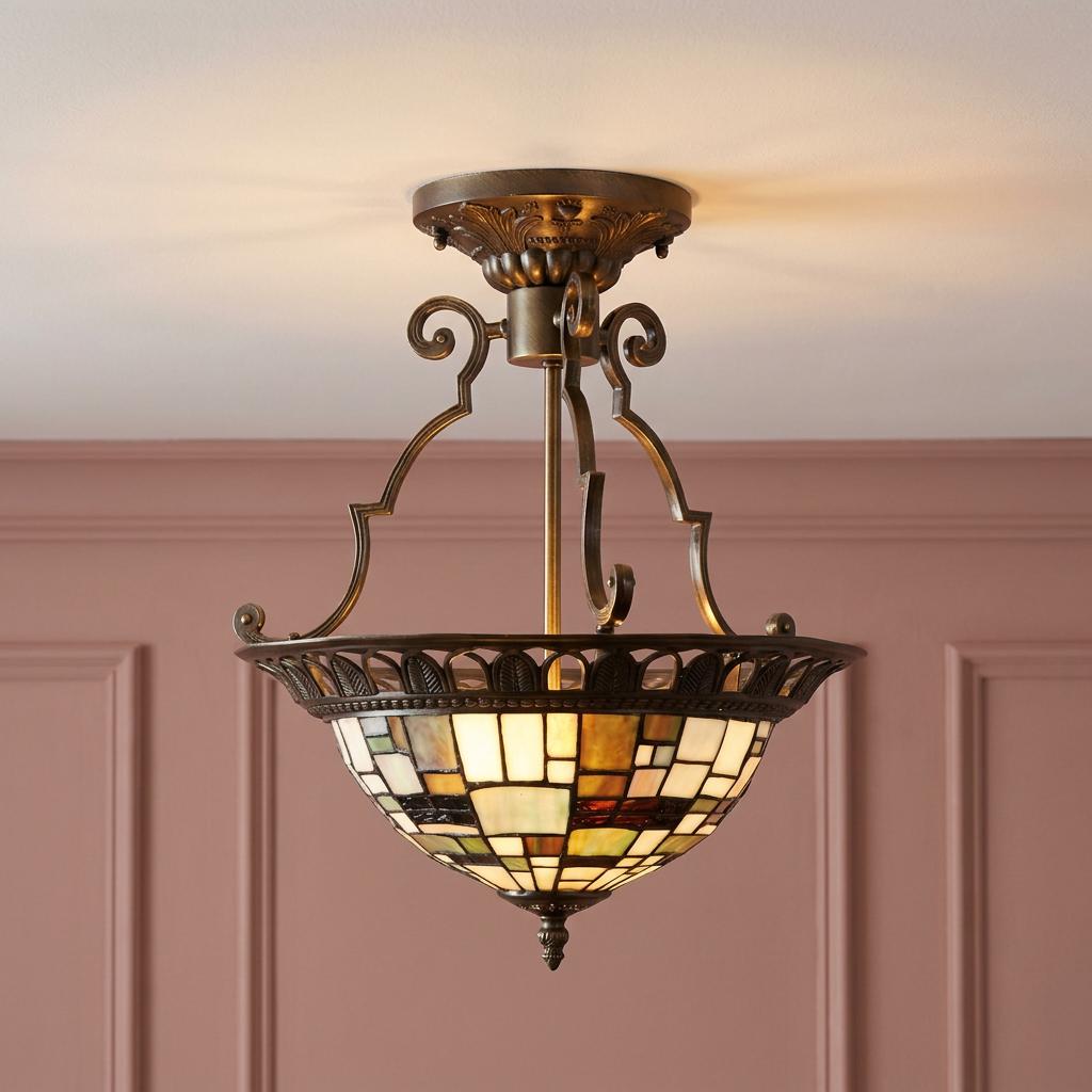 Geometric stained glass Tiffany-style semi-flush ceiling light with bronze hardware against a pink paneled wall.