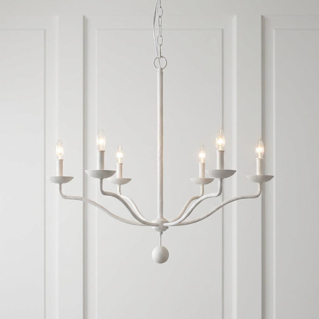 Feiss Annie six-light textured white chandelier with lit candle bulbs against a white paneled wall.