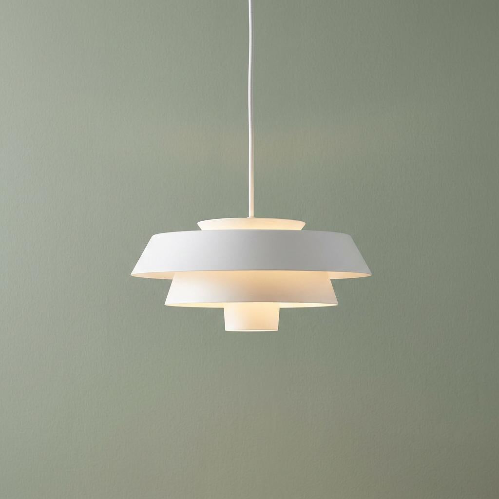 Feiss Brisbin 1 light matte white tiered pendant ceiling light illuminated against a sage green wall.