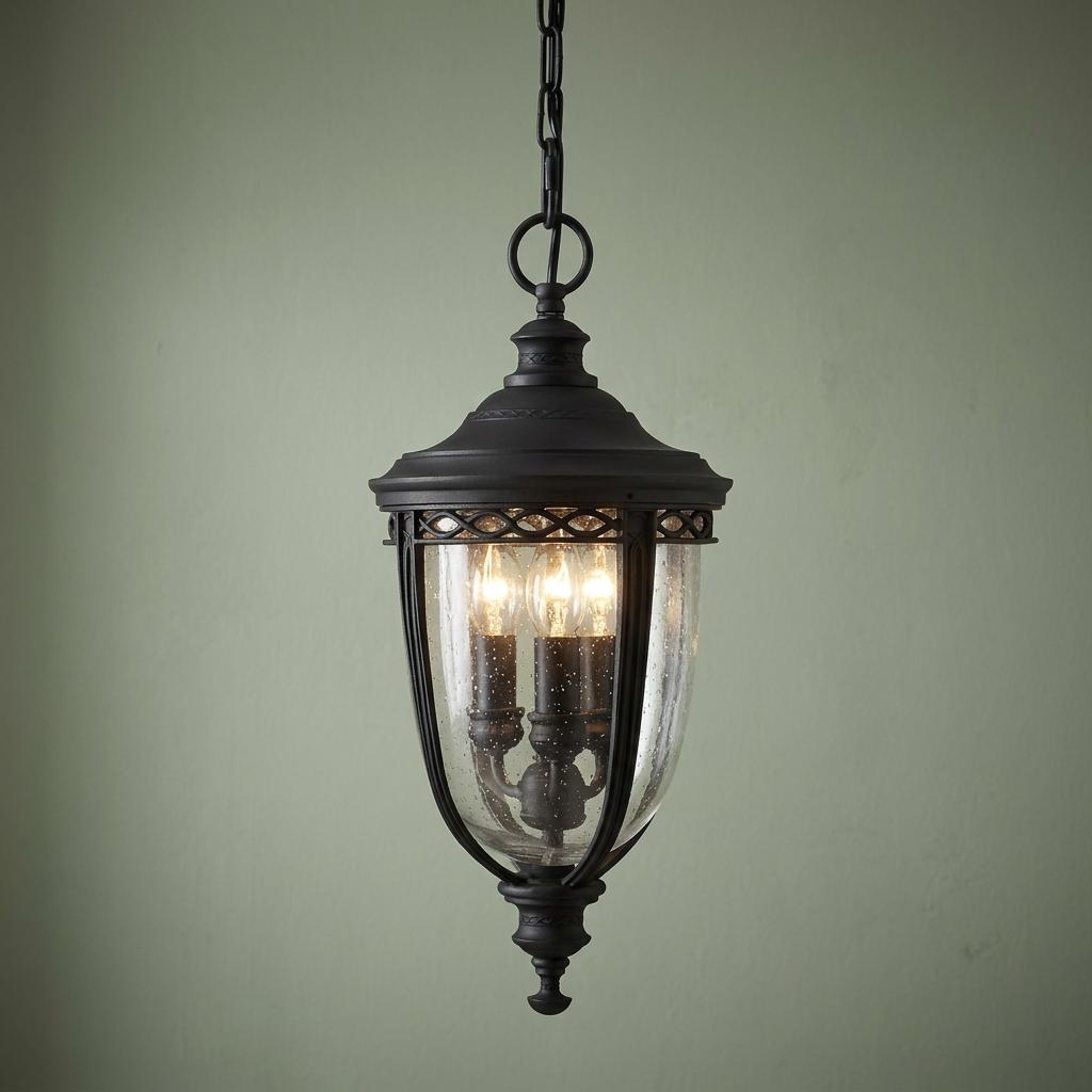 Feiss English Bridle black outdoor pendant light with seeded glass and three bulbs hanging against a green wall.