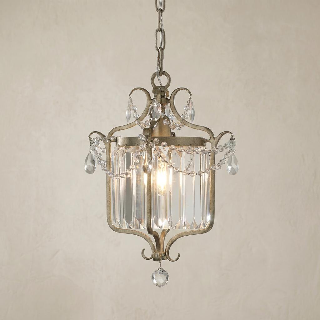 Silver leaf lantern with glass prism panels and draped crystal beads hanging against a neutral textured wall.