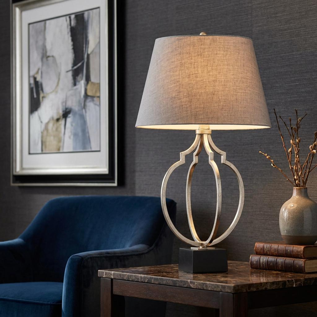 Feiss Grandeur table lamp with a silver open-frame base and grey shade on a marble table in a modern living room.