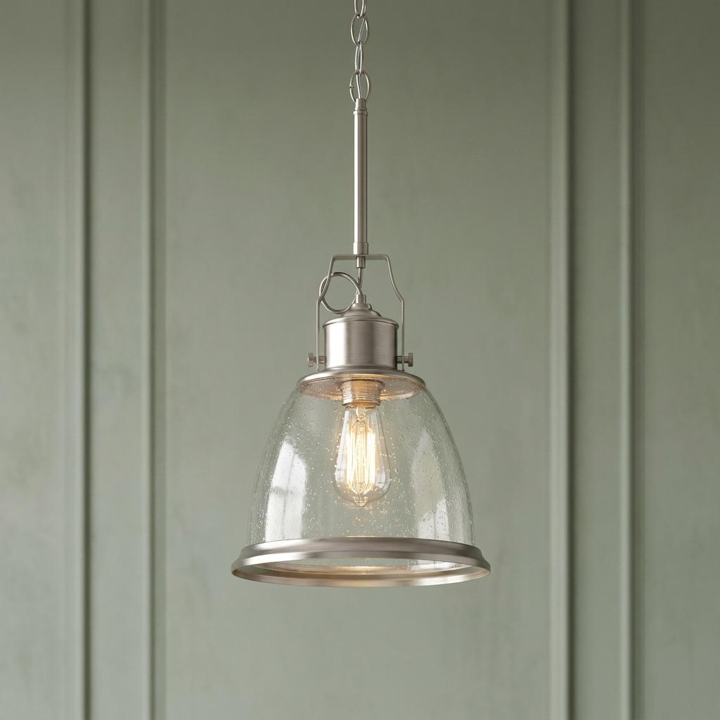 Feiss Hobson satin nickel pendant light with a seeded glass bell shade lit against a sage green wall.