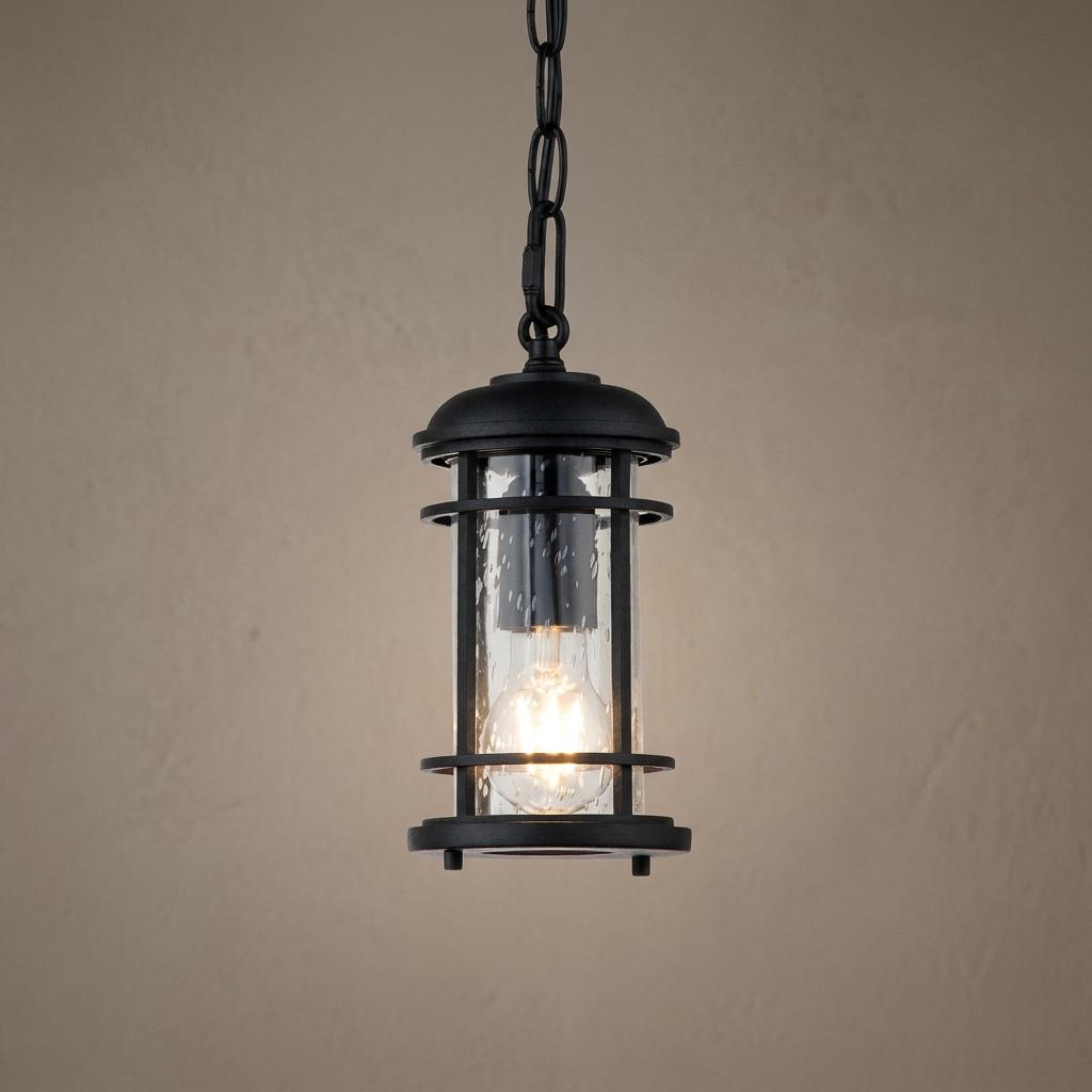 Feiss Lighthouse outdoor chain lantern with a black finish and clear seeded glass, illuminated against a neutral wall.