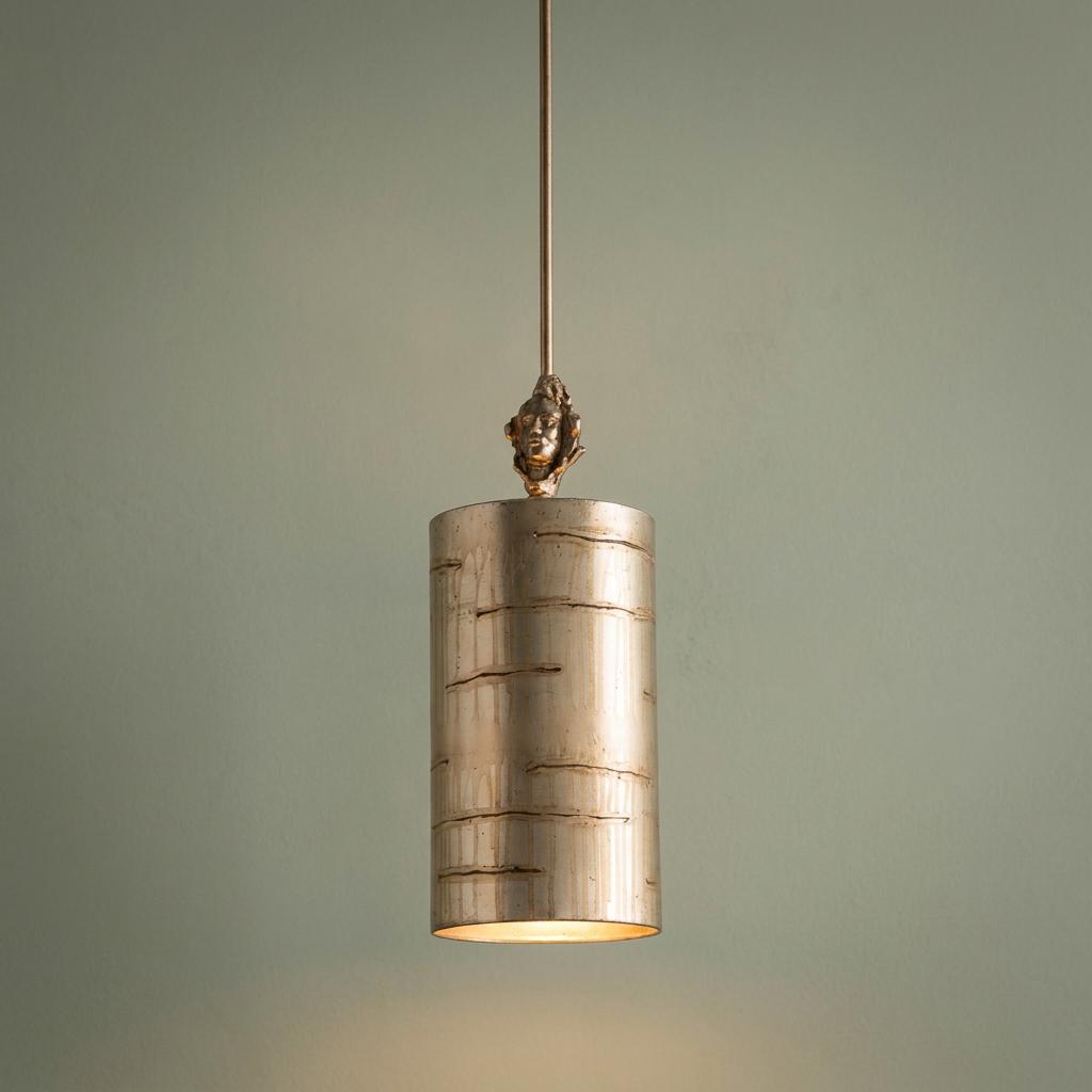 Flambeau Fragment silver cylinder pendant light with birch bark texture and face sculpture against a plain wall.