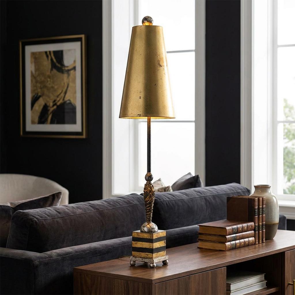 Table lamp with a gold conical shade and striped base sits on a wooden console table in a dark-walled living room.