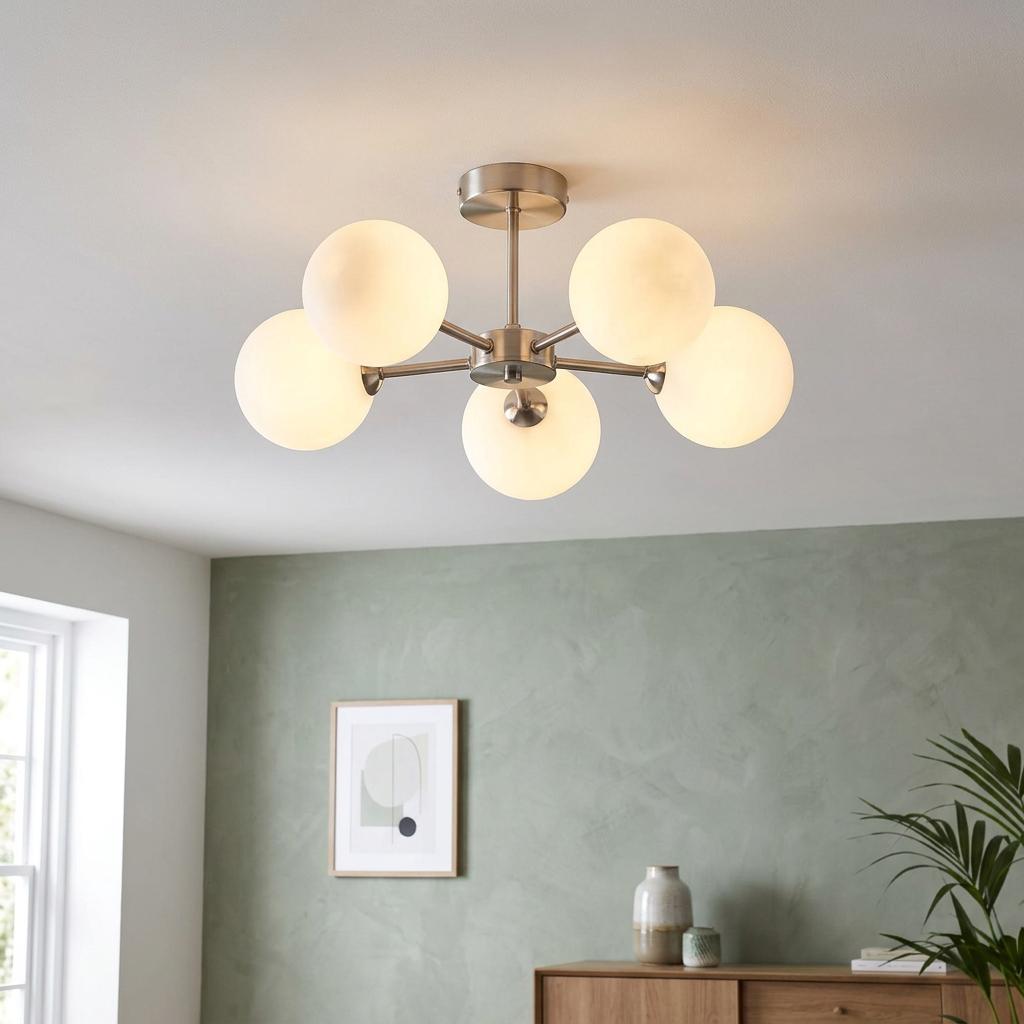 Five-arm satin nickel semi-flush ceiling light with glowing opal glass globes in a modern green-walled room.