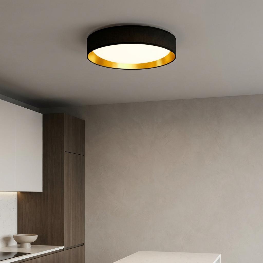 Circular black ceiling flush light with a gold inner rim and white diffuser in a minimalist kitchen setting.