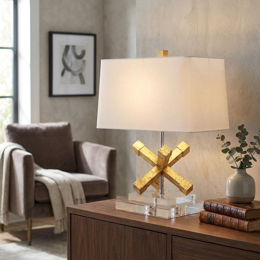 Gold jack-shaped table lamp with a rectangular white shade on a wooden cabinet.