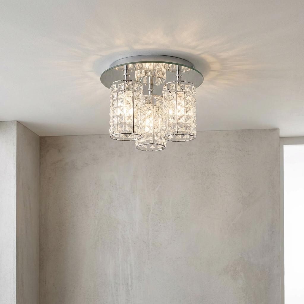 Glamour chrome 3-light semi-flush ceiling fixture with crystal cylinder shades casting light on a white ceiling.