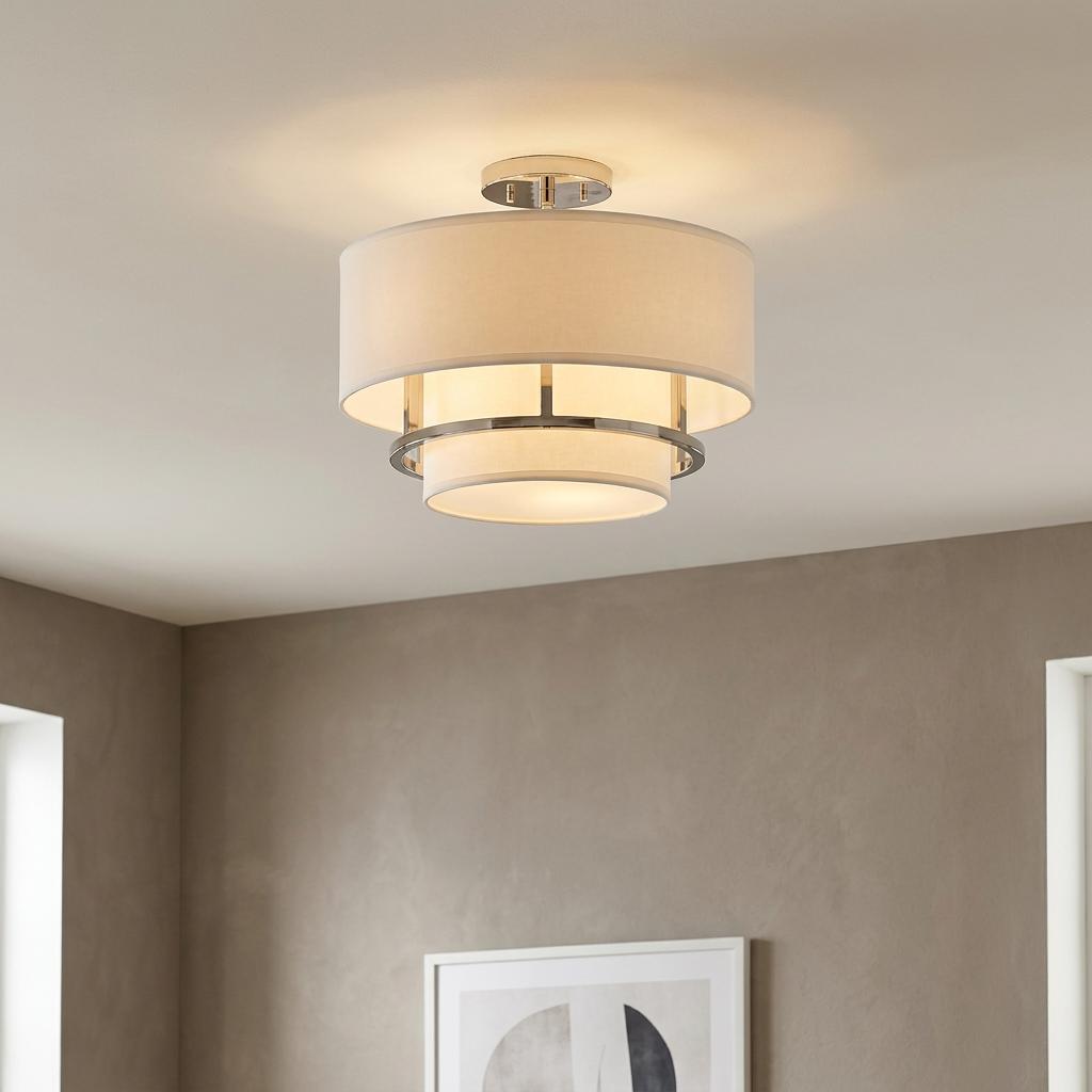 Polished nickel two-tier white drum shade semi-flush ceiling light illuminated in a contemporary room.