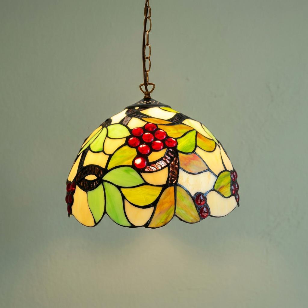 Tiffany-style pendant light featuring red glass grapes and green leaves on a cream stained glass shade.