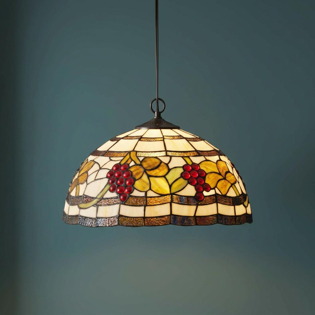 Stained glass Tiffany pendant light with red grape clusters and yellow leaves on a dark teal background.