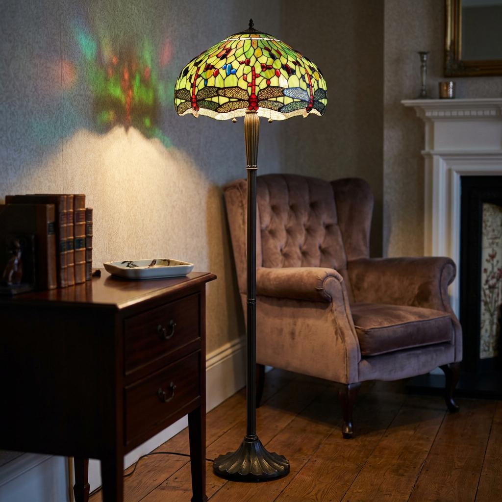Green Dragonfly Tiffany floor lamp casting colorful patterns on a wall beside a plush armchair.