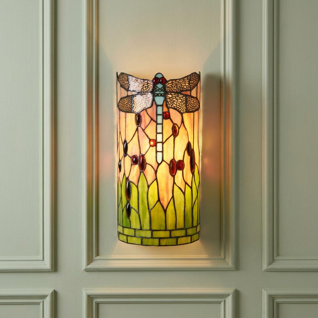 Illuminated Tiffany wall light with a dragonfly and green glass reeds on a pale green paneled wall.