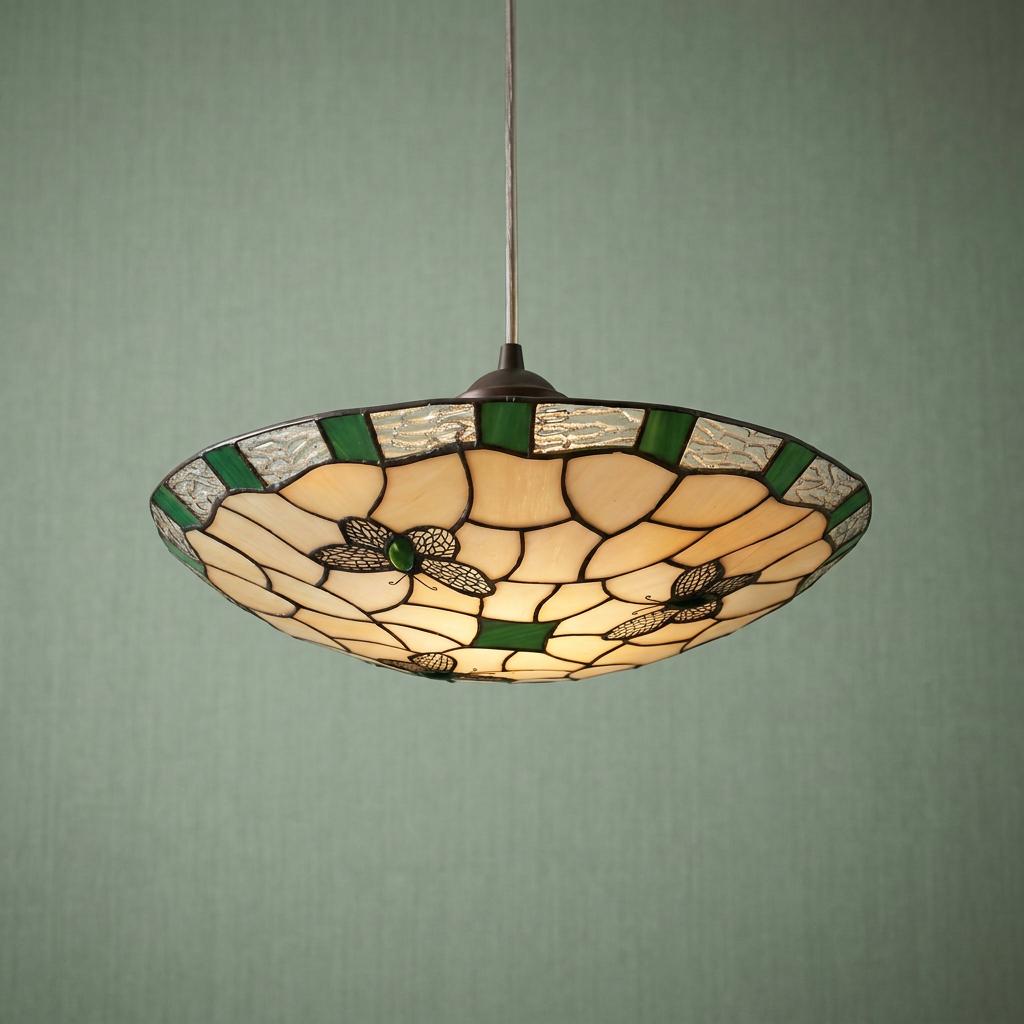 Lit Tiffany-style ceiling lamp shade featuring green butterfly stained glass motifs against a textured green wall.