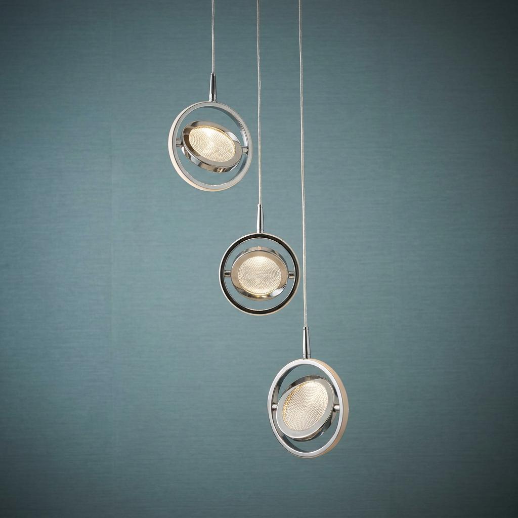 Three staggered chrome ring pendant lights with glowing crystal LED discs against a textured teal wall.