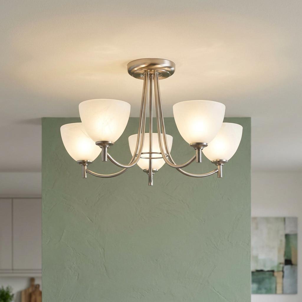 Five-arm antique chrome ceiling light with glowing frosted glass shades mounted on a ceiling above a green wall.