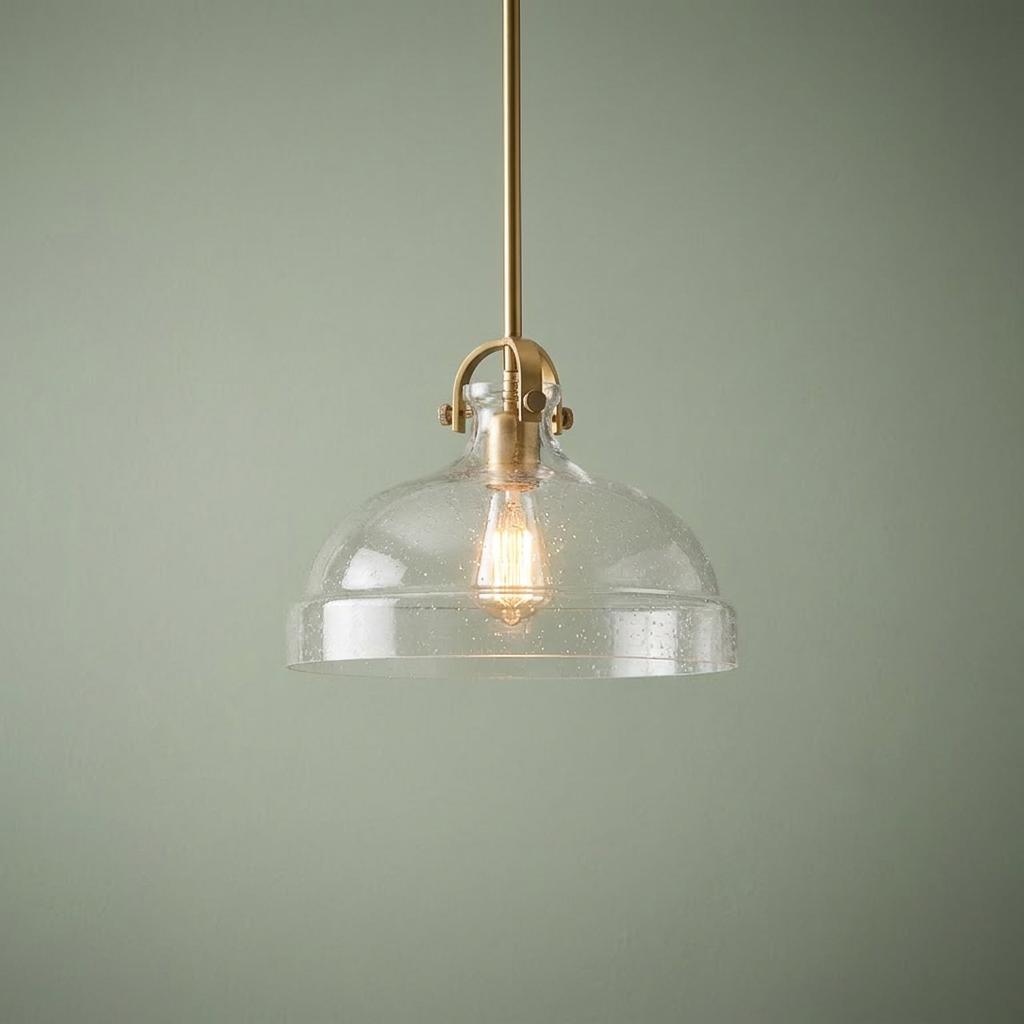 Hampton brass pendant light featuring a blown seed glass dome shade on a sage green background.