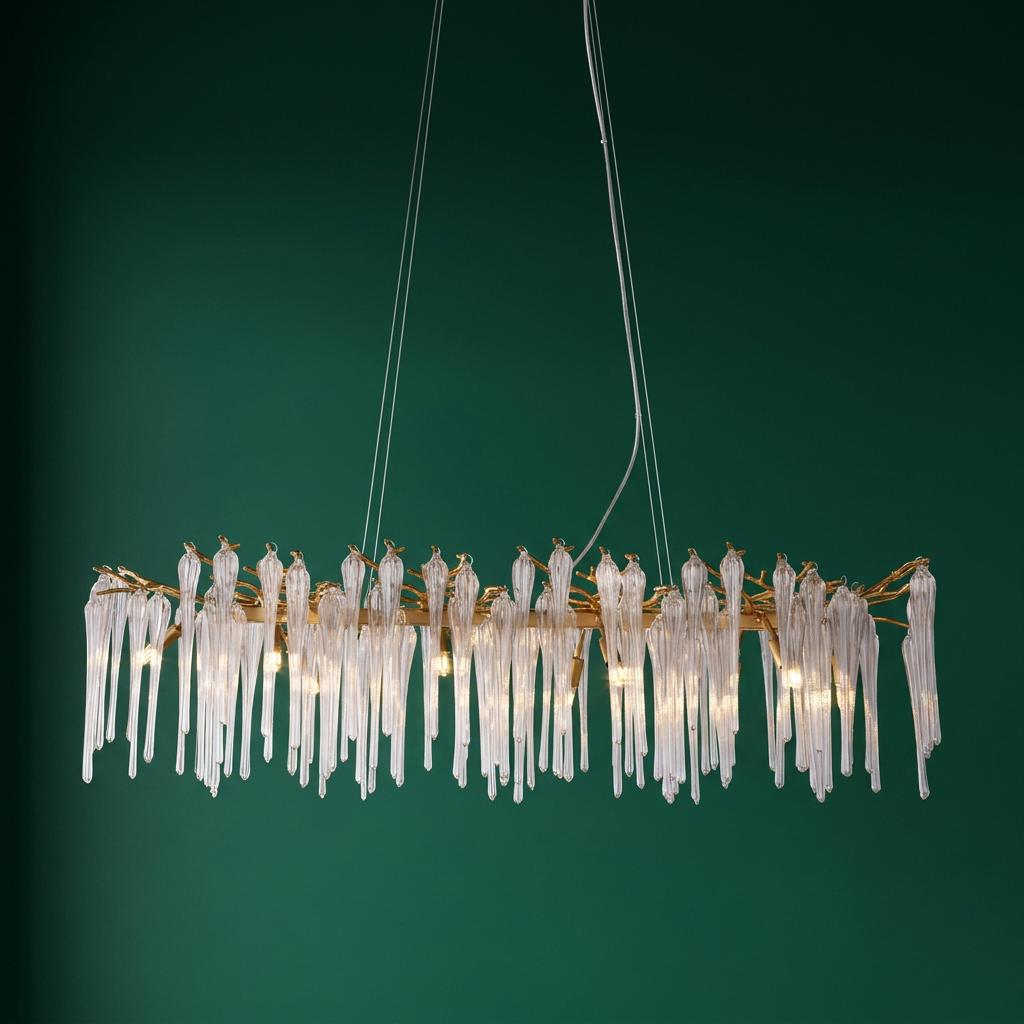 A modern rectangular chandelier with elongated clear glass droplets on a gold frame against a dark green background.