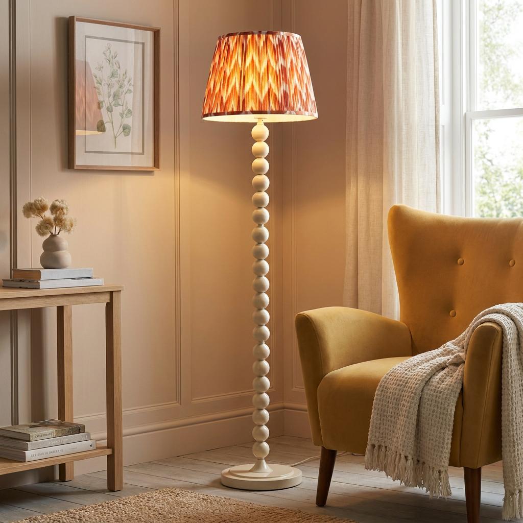 Almond white bobbin floor lamp with an orange zigzag shade in a cozy living room beside a yellow armchair.