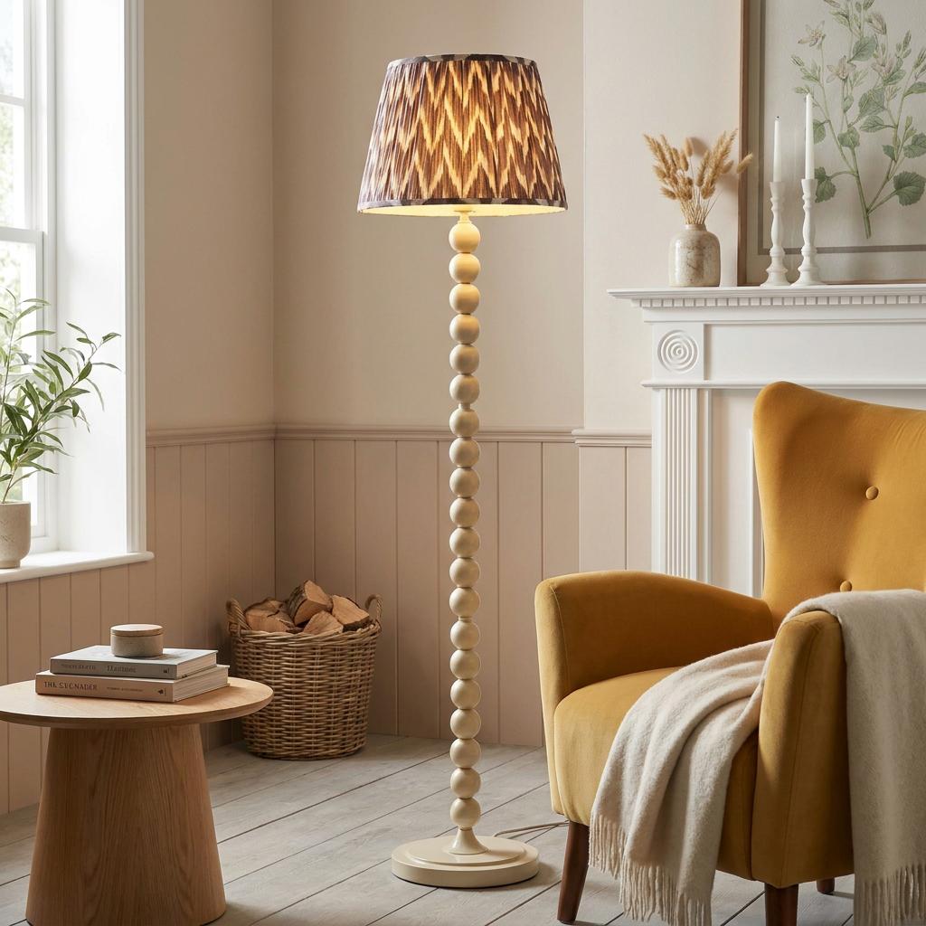 Almond white bobbin floor lamp with a zigzag shade standing next to a yellow armchair in a cozy living room.