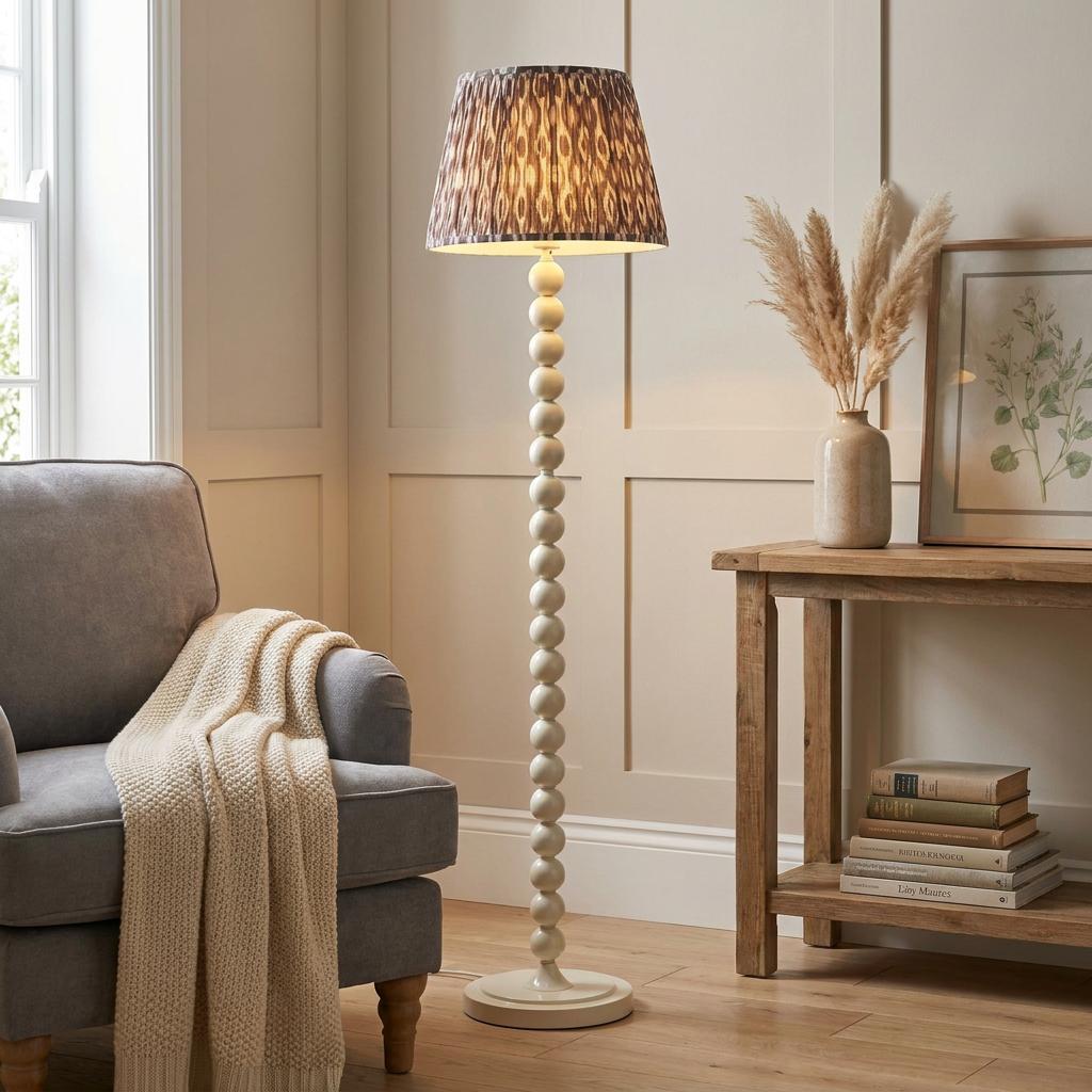 Higgledy almond white floor lamp with a grey ikat shade in a cozy living room with a grey armchair.