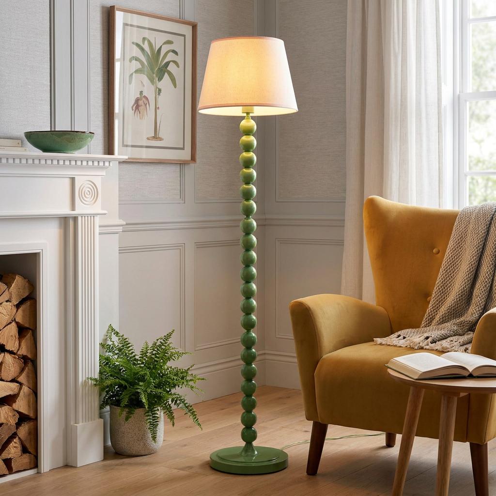 Higgledy green bobbin floor lamp with a white shade standing next to a yellow armchair in a neutral living room.