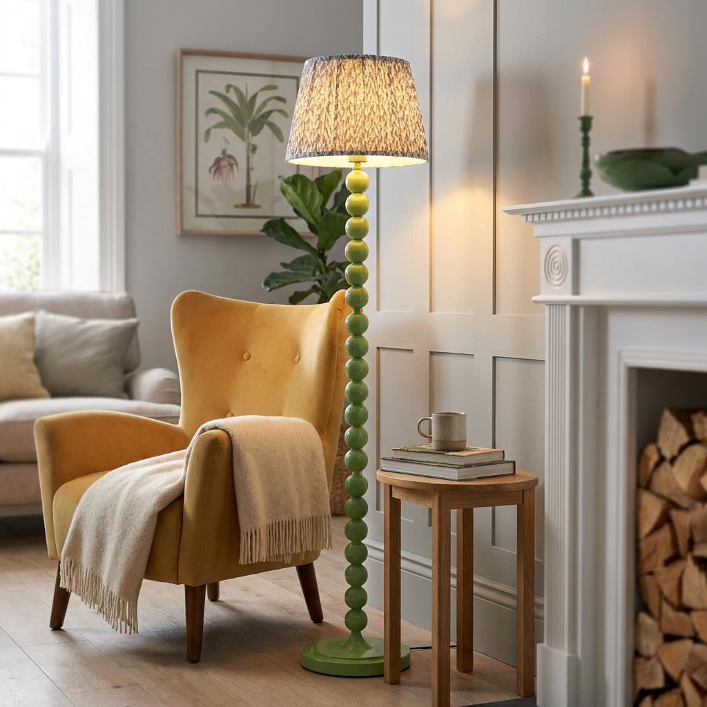 Green bobbin floor lamp with a patterned grey shade next to a yellow armchair in a warm living room.