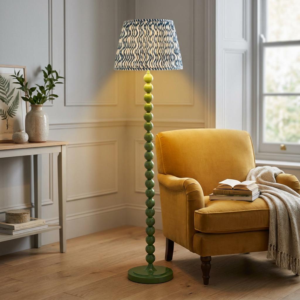 Green bobbin floor lamp with a blue patterned shade next to a yellow armchair in a light-filled room.