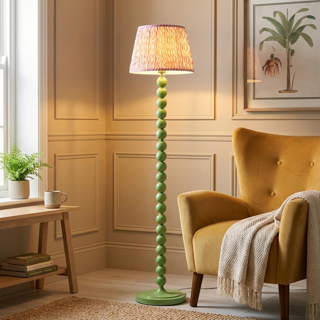 Higgledy green bobbin floor lamp with a pink ripple shade next to a yellow armchair in a cozy living room.