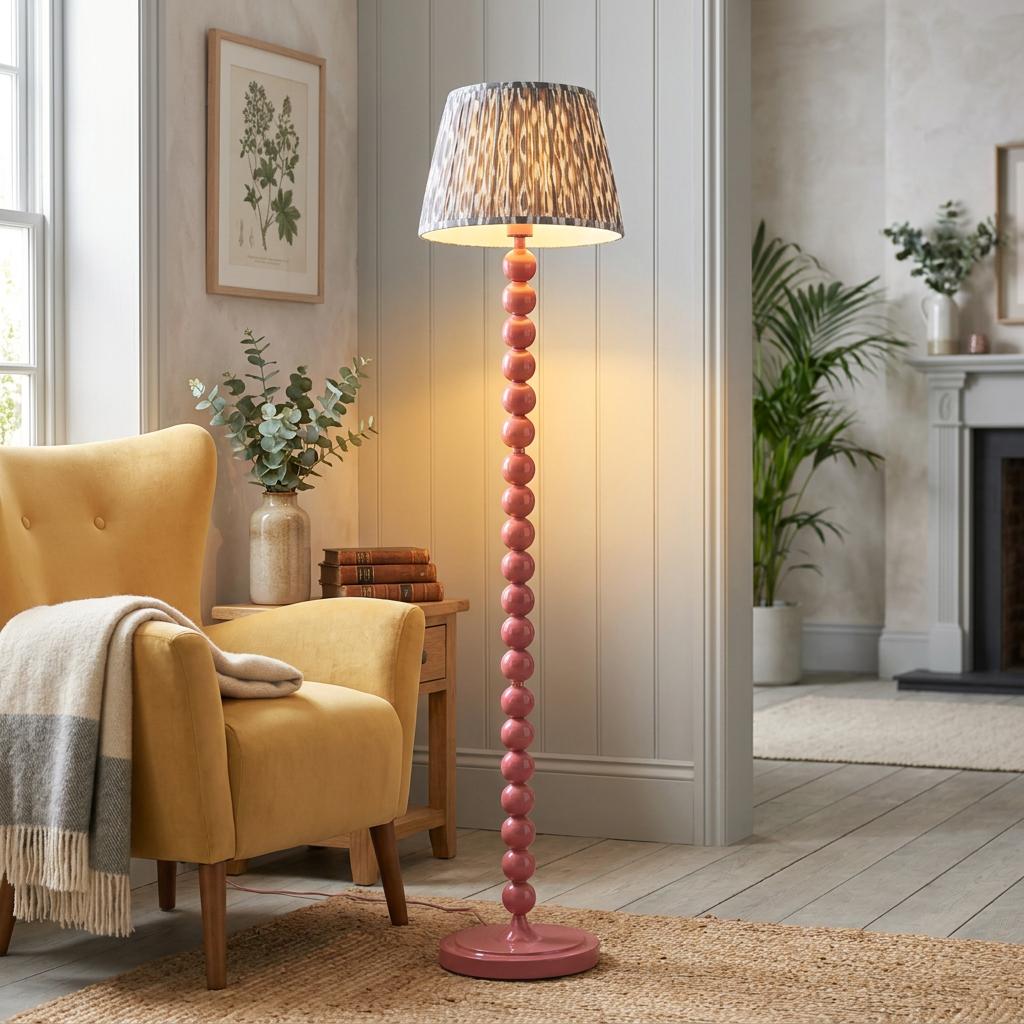 Pink beaded floor lamp with a grey ikat shade stands next to a yellow armchair in a cozy living room.