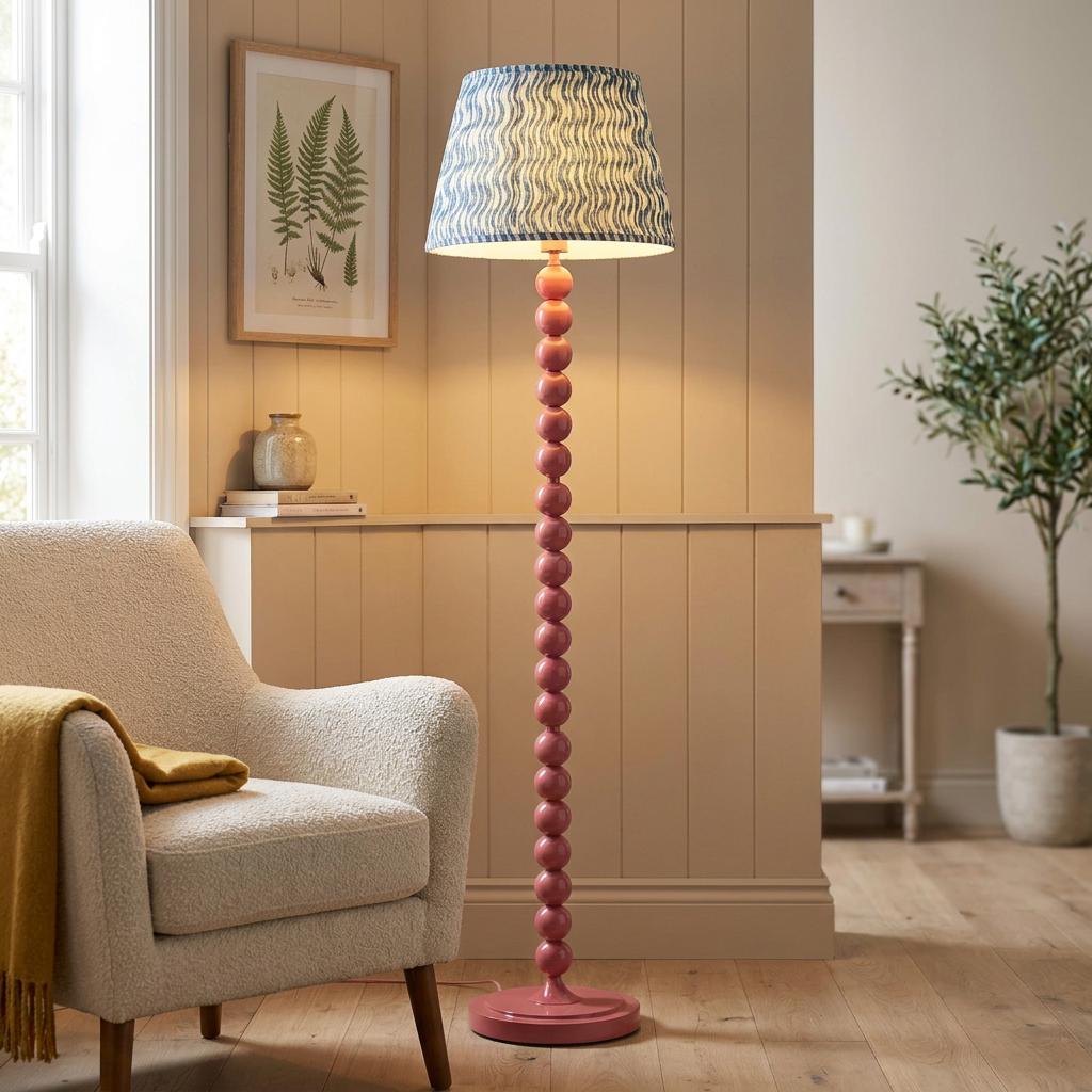 Higgledy pink floor lamp with a blue ripple shade beside a cream armchair in a warm-toned living room.