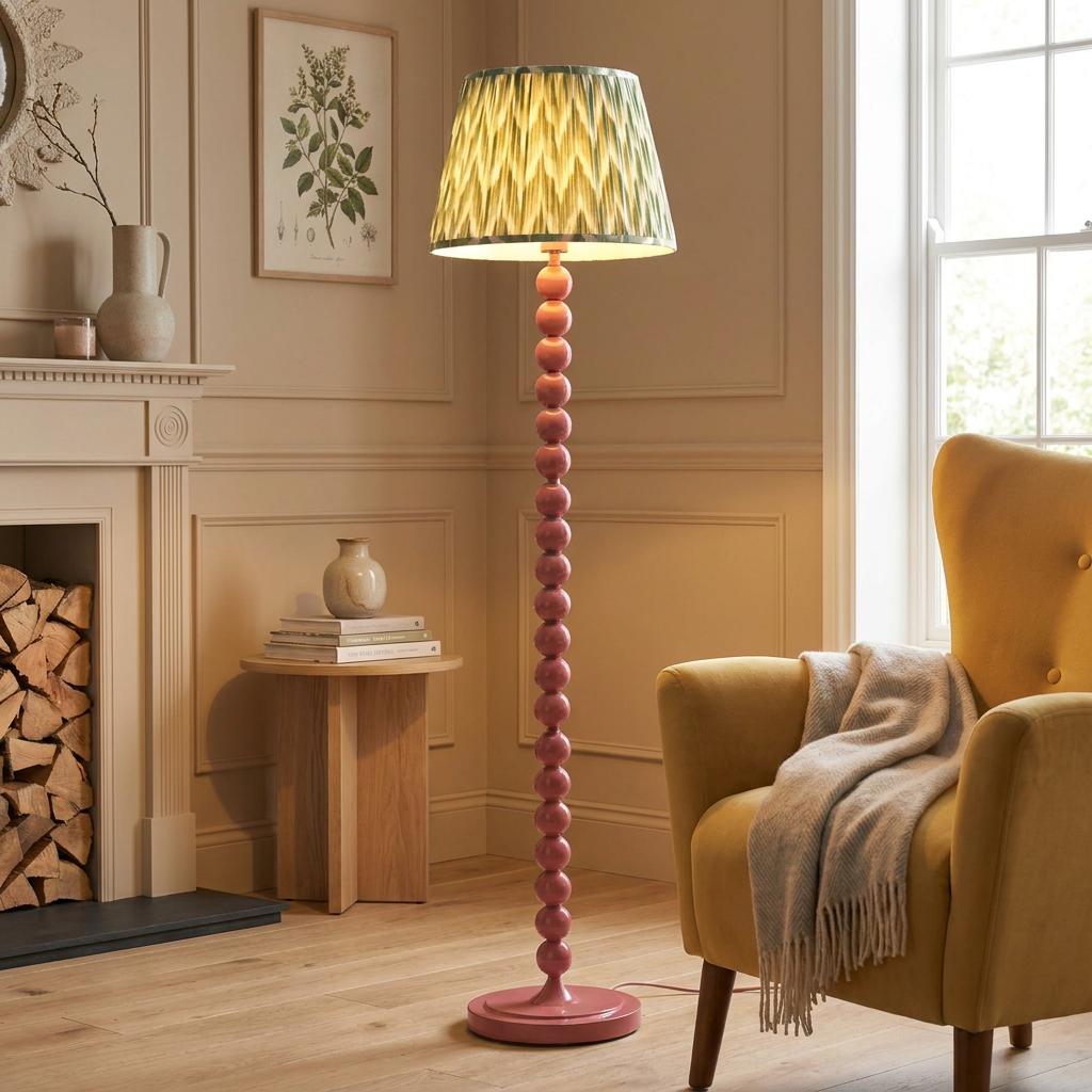 Pink beaded floor lamp with a zigzag green shade in a living room beside a yellow armchair.