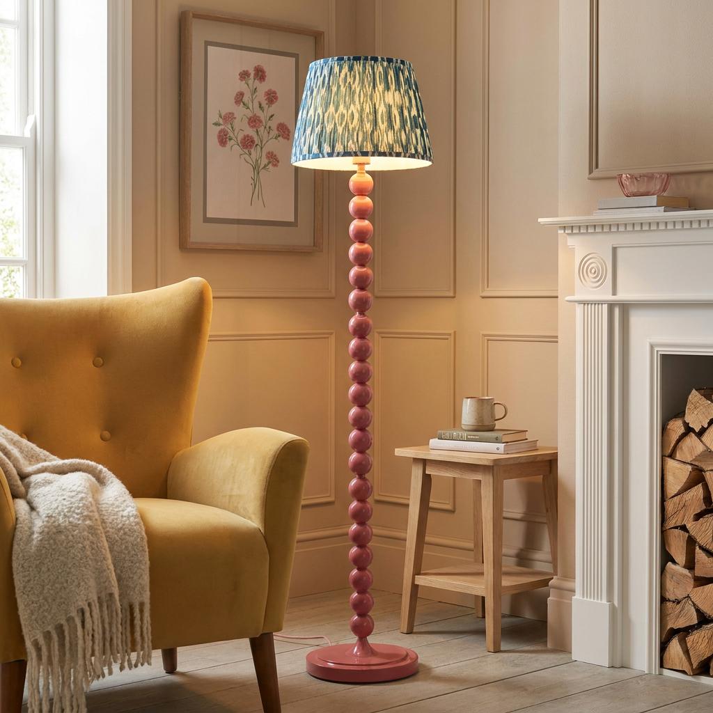 Pink beaded floor lamp with a blue Ikat shade beside a yellow armchair in a cozy living room setting.
