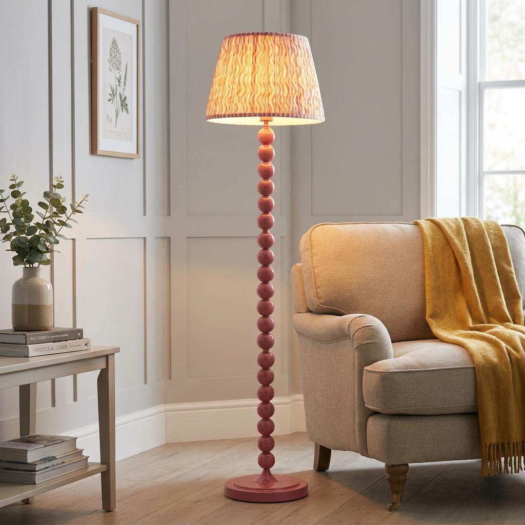 Pink bobbin floor lamp with a coral patterned shade next to a beige armchair in a classic living room.