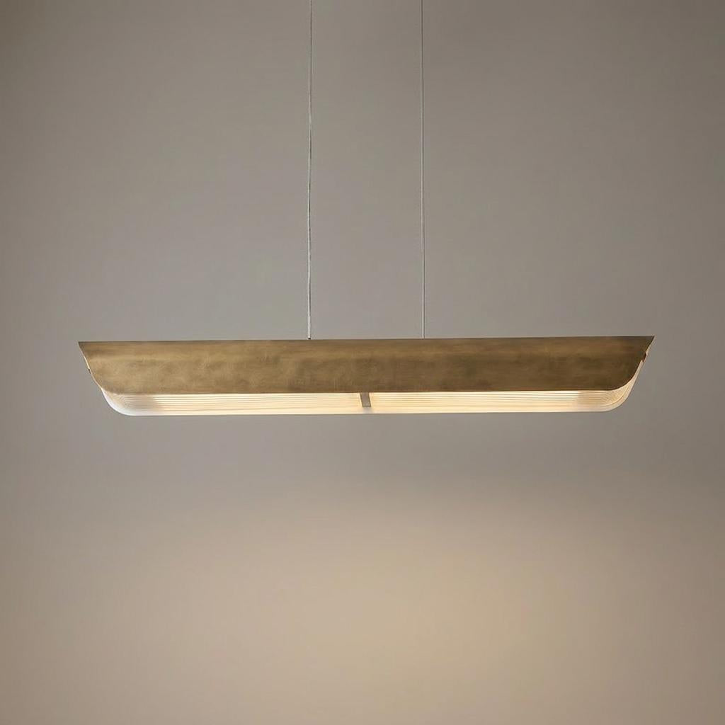 Linear brass LED pendant light with a ribbed glass diffuser suspended from two thin wires.