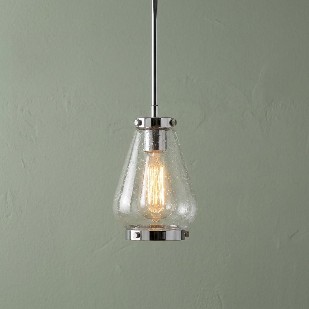 Hinkley Finley mini pendant light in chrome with a seeded glass shade and glowing Edison bulb against a green wall.