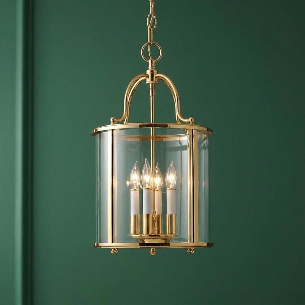 Polished brass four-light ceiling lantern with clear glass, hanging against a deep green background.