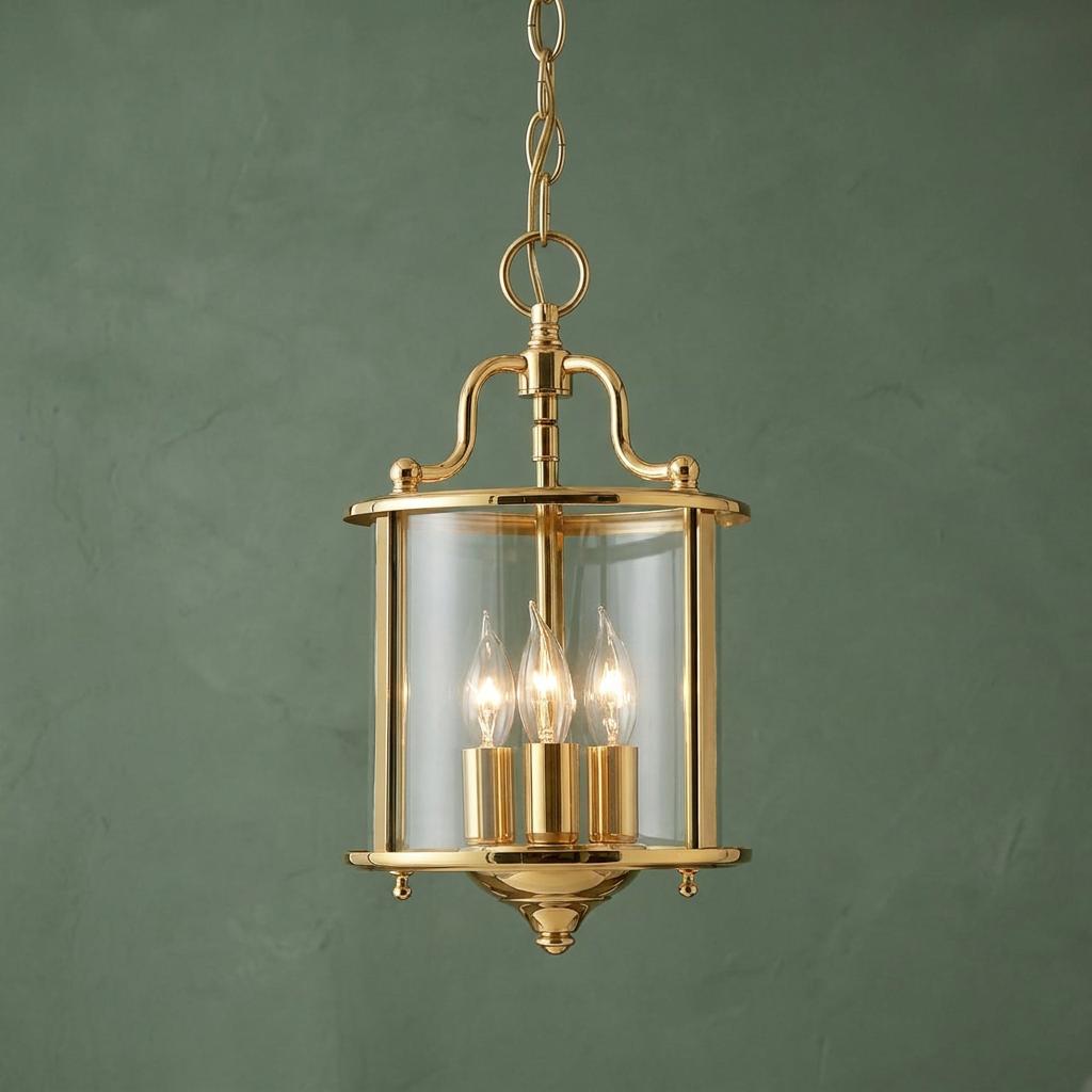 Hinkley Gentry polished brass 3-light ceiling lantern with clear glass, hanging against a green textured wall.