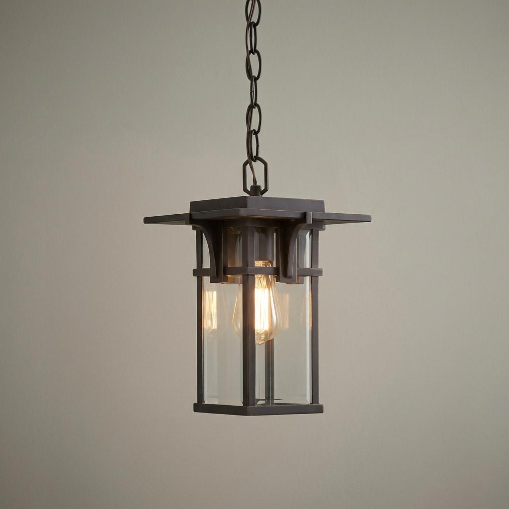 Hinkley Manhattan oil-rubbed bronze outdoor pendant light with clear glass panels and a glowing Edison bulb.