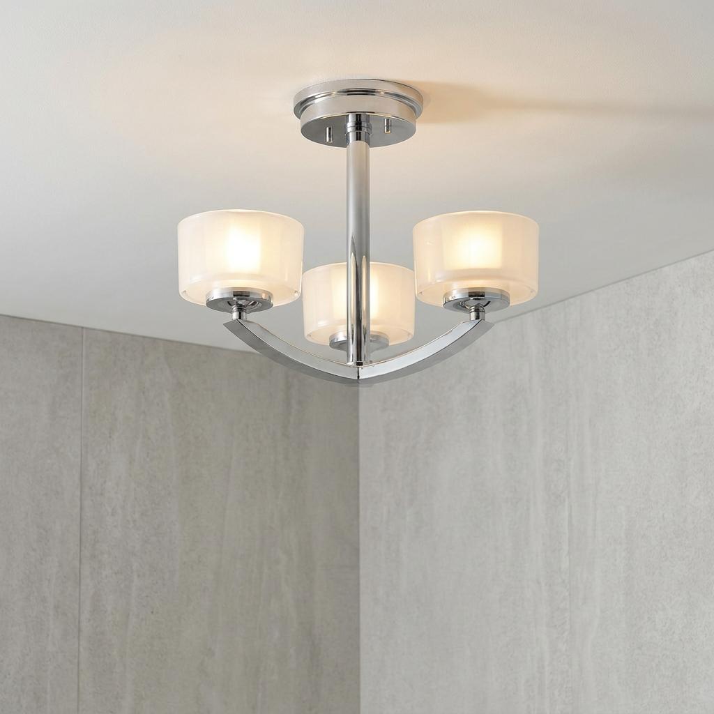Three-light chrome semi-flush ceiling fixture with frosted glass shades mounted in a modern gray bathroom.
