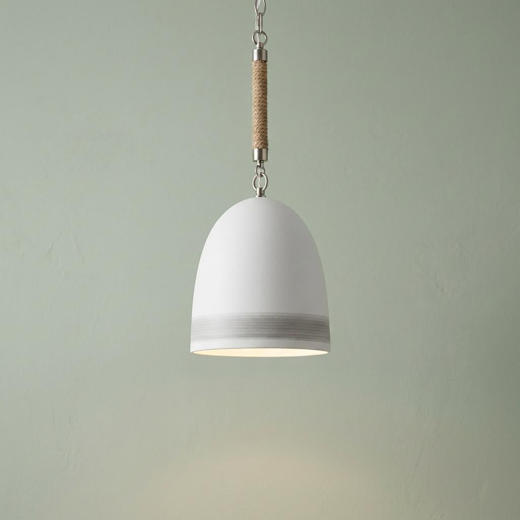 White dome pendant light with a rope-wrapped cord and grey stripe, hanging against a textured sage green wall.