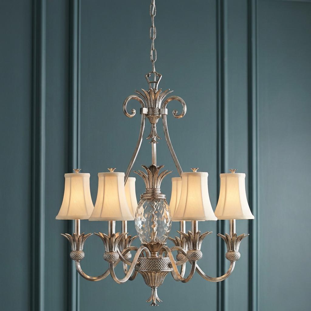 A 7-light chandelier in polished antique nickel with pineapple motifs and fabric shades against a teal paneled wall.
